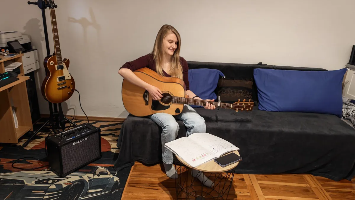 Odrasla polaznica svira akustičnu gitaru na satu gitare u Novom Zagrebu