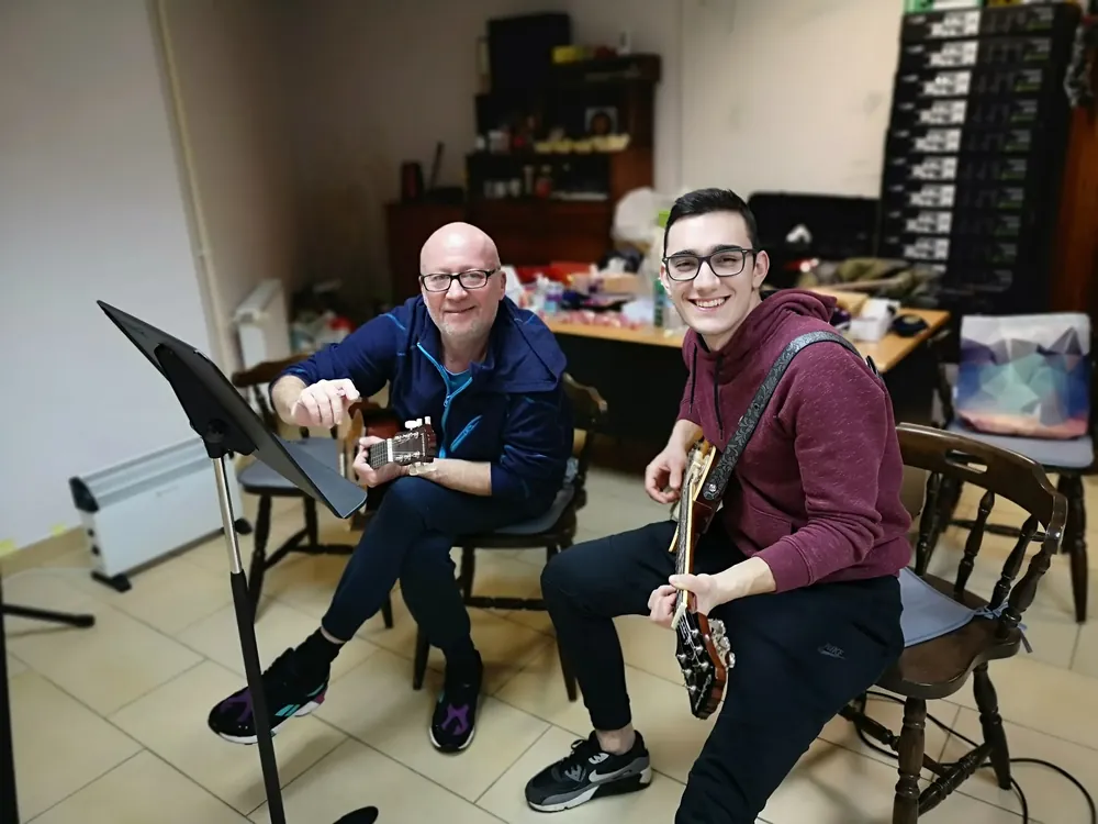 Učitelj gitare svira gitaru s prijateljem na prijateljskoj svirci